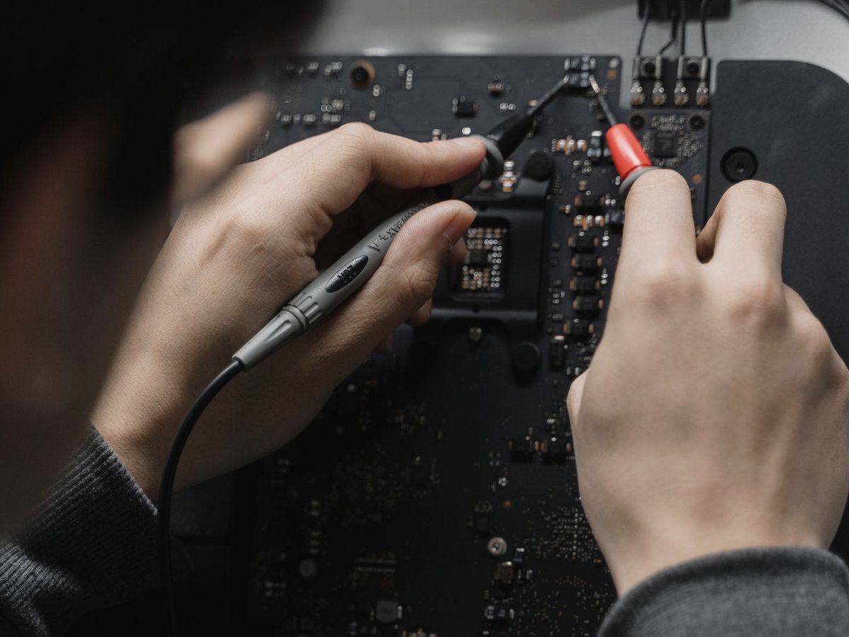 Hands testing an electronic circuit board